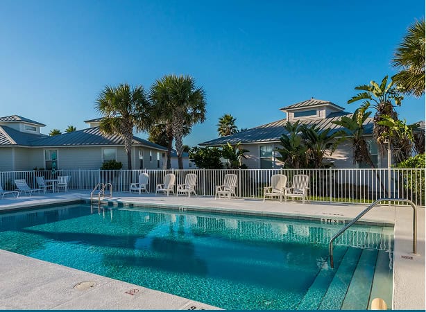 Pool at Devil's Elbow Fishing Resort with lounge chairs and palm trees.