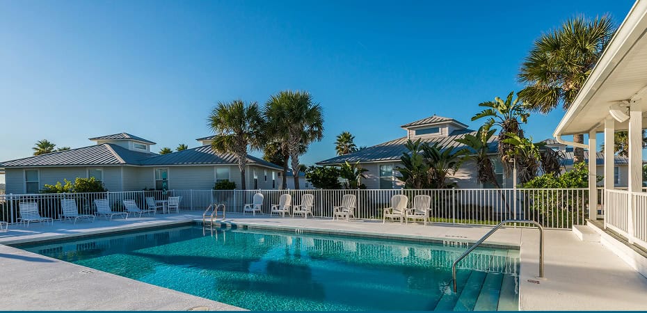 Scenic view of the swimming pool at Devil's Elbow Fishing Resort with palm trees and clear blue sky.